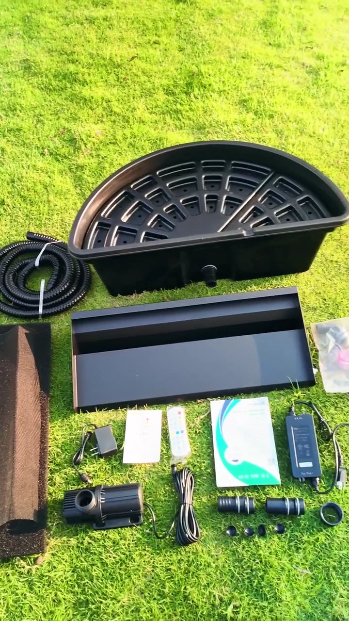 The basin, spillway, pump, tubing and accessories laid out on the lawn.